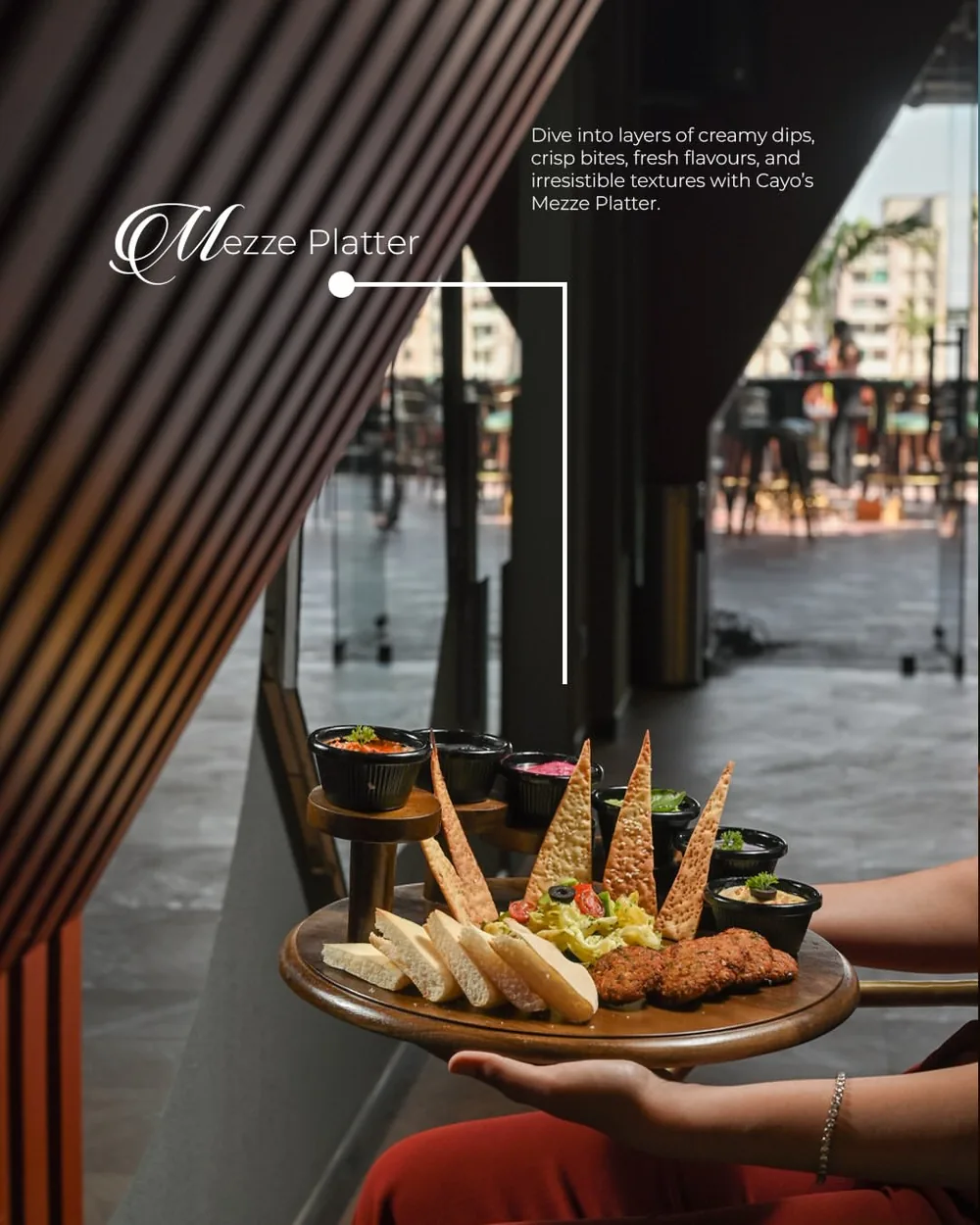 A wooden board of dips, lavash, pita and falafel carried through the restaurant