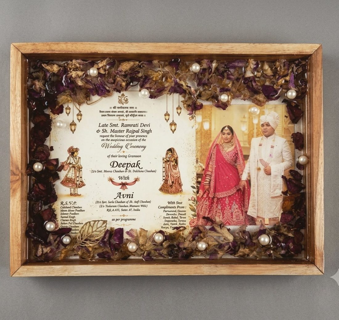 A wooden tray frame holding a wedding invitation and a couple's photo, ringed with dark rose petals and pearls in resin