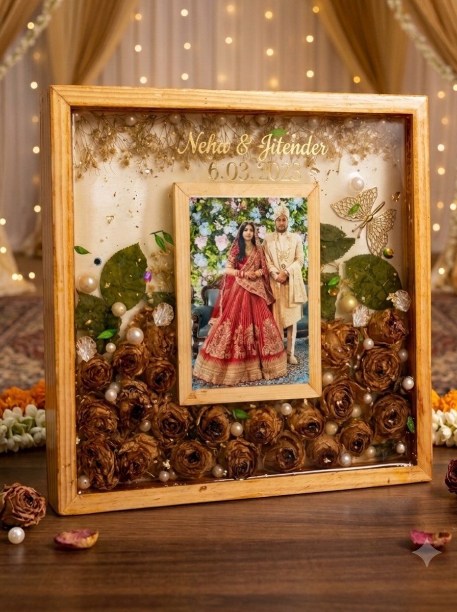 A wooden box frame with a couple's photo, dried rosebuds, pearls and gold lettering set in resin