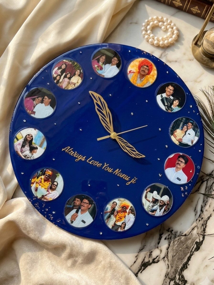 A deep blue resin wall clock with twelve round family photos, gold lettering and gold leaf-shaped hands