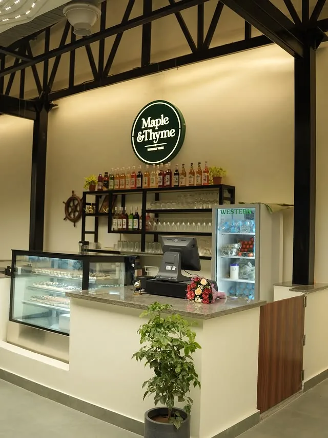 The cafe counter under the Maple and Thyme sign, with the syrup shelf and dessert case