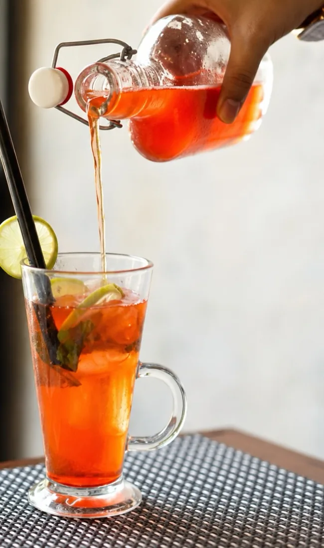 A chilled red cooler being poured over lime and mint
