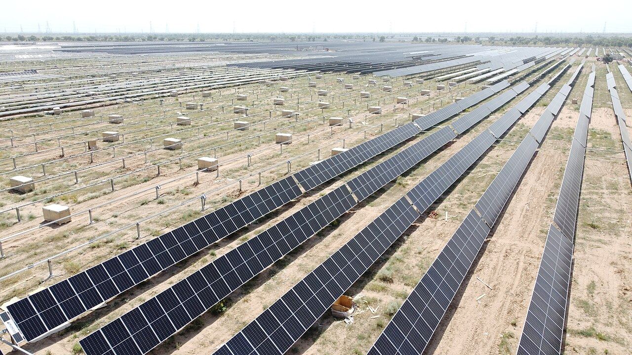 Long rows of solar panels across a large solar power plant in the Rajasthan desert