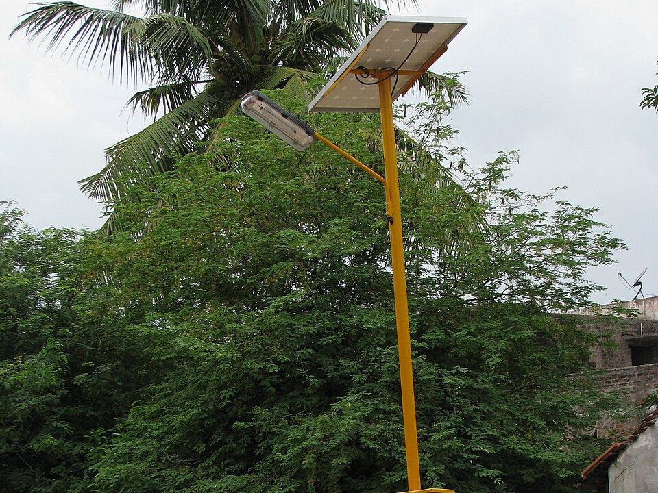 Solar street light on a yellow pole with a panel above the lamp